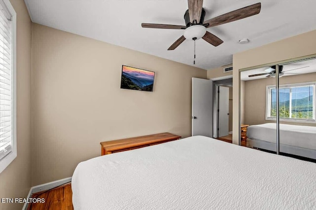 bedroom with ceiling fan, wood finished floors, visible vents, and baseboards