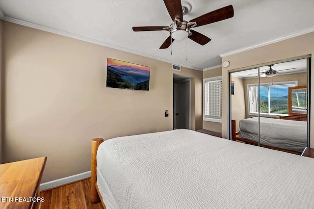 bedroom featuring visible vents, ornamental molding, wood finished floors, baseboards, and ceiling fan