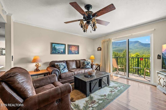 living room featuring ceiling fan, baseboards, wood finished floors, and crown molding