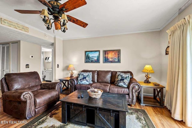 living room with light wood-style flooring, a ceiling fan, and ornamental molding