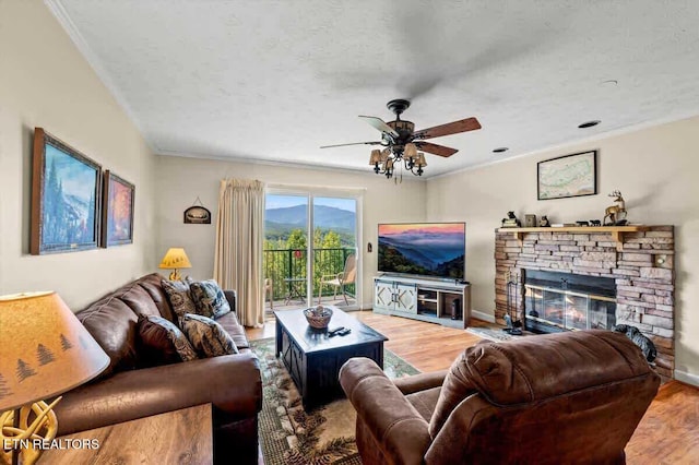 living area featuring a fireplace, baseboards, ceiling fan, and wood finished floors