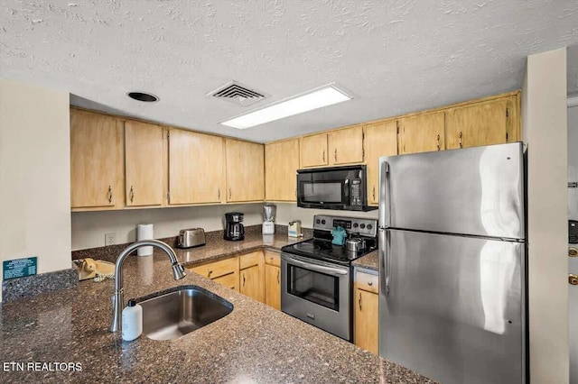 kitchen with a sink, visible vents, appliances with stainless steel finishes, and light brown cabinetry