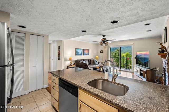 kitchen with light tile patterned floors, a sink, stainless steel appliances, a textured ceiling, and open floor plan