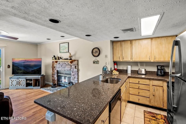 kitchen featuring visible vents, a peninsula, stainless steel appliances, a sink, and open floor plan