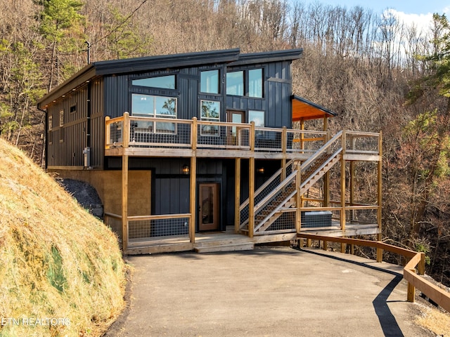 rear view of property with a wooden deck, board and batten siding, and stairway