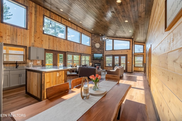 dining space with wooden ceiling, a wealth of natural light, a fireplace, and wood walls