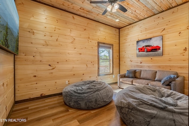 sitting room with wood walls, wood ceiling, ceiling fan, and wood finished floors