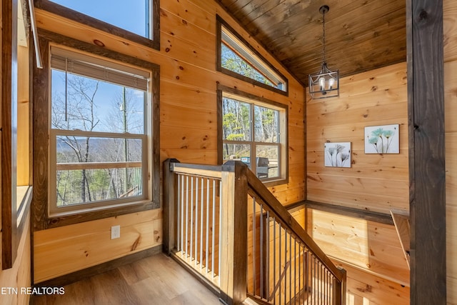 stairway featuring a wealth of natural light, wooden walls, wooden ceiling, and lofted ceiling