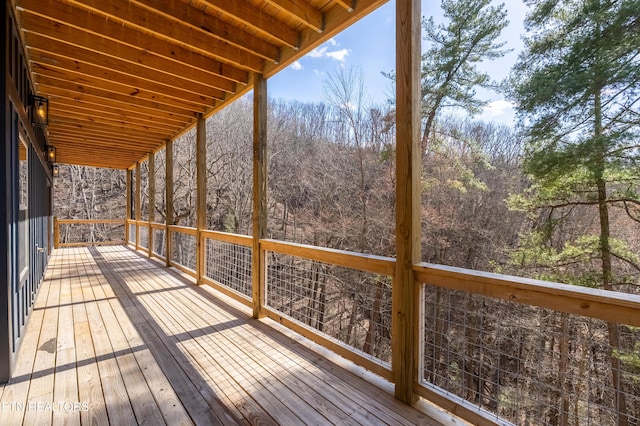 wooden terrace featuring a wooded view