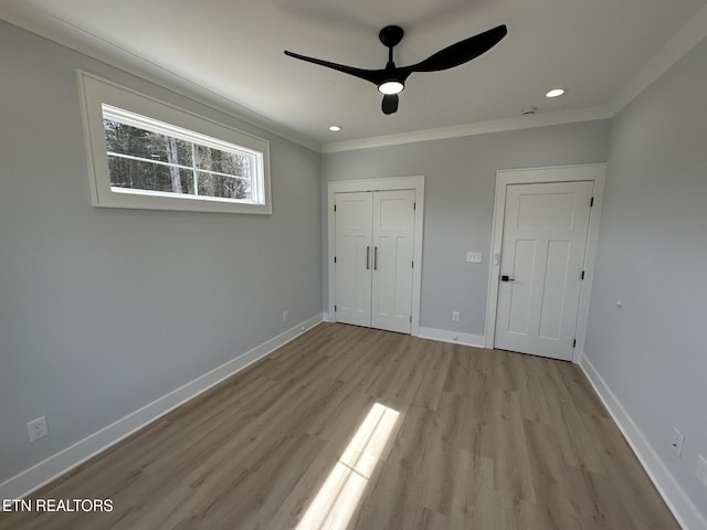 unfurnished bedroom with crown molding, baseboards, recessed lighting, light wood-style floors, and a closet