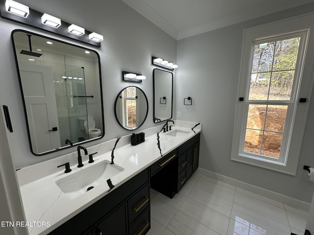 bathroom featuring a sink, baseboards, a stall shower, and double vanity