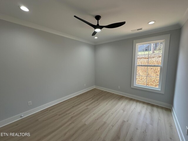 spare room featuring crown molding, wood finished floors, a ceiling fan, and baseboards