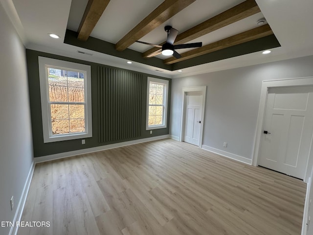 spare room featuring a wealth of natural light, beamed ceiling, light wood-type flooring, and baseboards