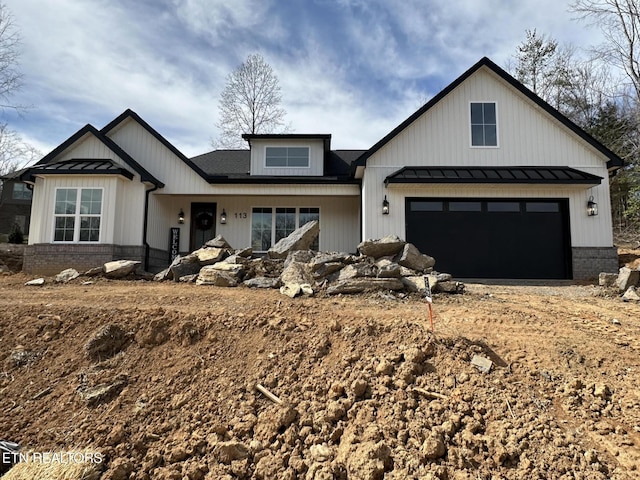 modern farmhouse featuring metal roof, brick siding, an attached garage, and a standing seam roof