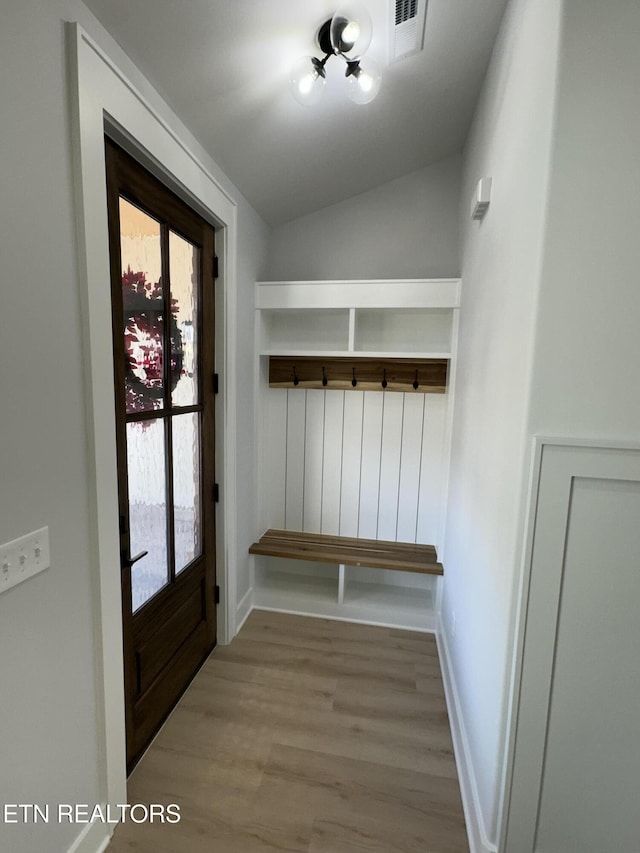 mudroom with baseboards, lofted ceiling, visible vents, and wood finished floors