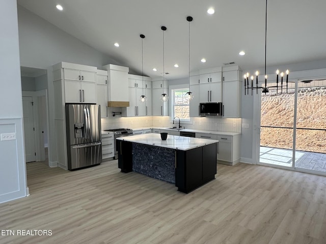 kitchen featuring premium range hood, a notable chandelier, a sink, a center island, and appliances with stainless steel finishes