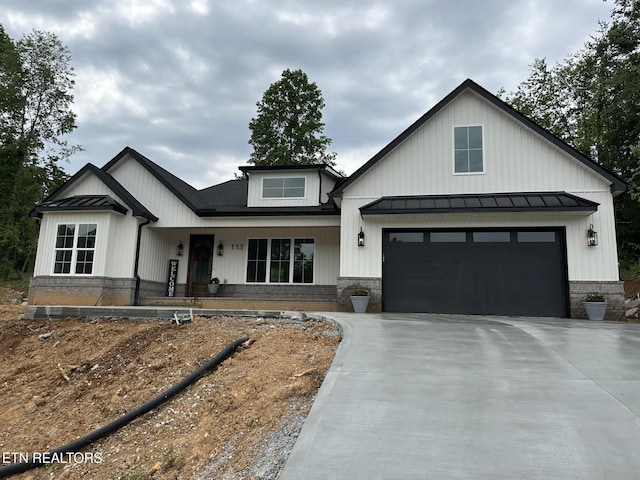 modern inspired farmhouse featuring driveway, a standing seam roof, a garage, and metal roof
