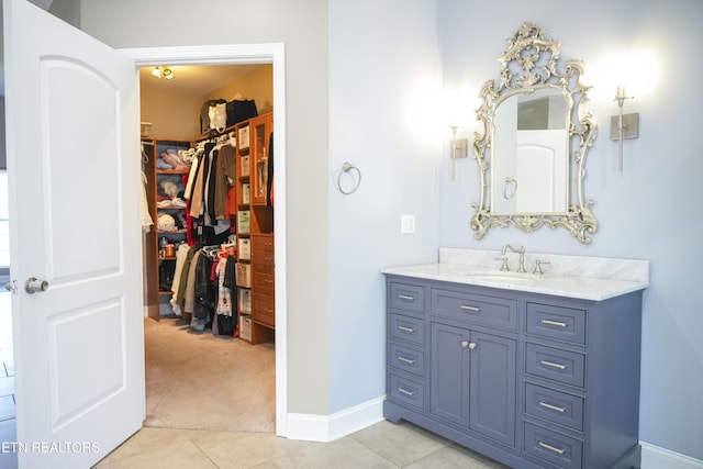 bathroom featuring tile patterned floors, a spacious closet, vanity, and baseboards