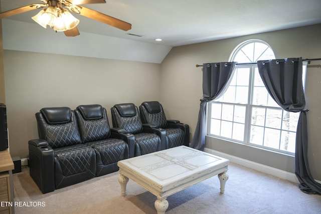 carpeted home theater room with vaulted ceiling, visible vents, baseboards, and ceiling fan