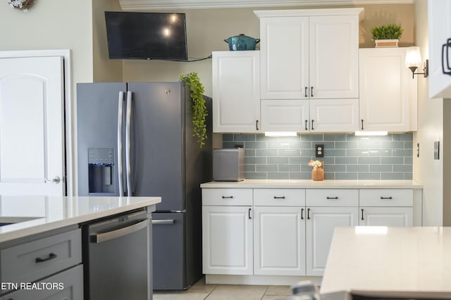 kitchen with stainless steel appliances, white cabinetry, backsplash, and light countertops