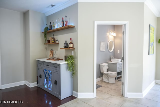 interior space featuring visible vents, a sink, crown molding, baseboards, and a dry bar