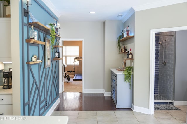 corridor featuring visible vents, baseboards, crown molding, and tile patterned flooring