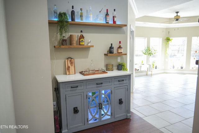 bar featuring a dry bar, a raised ceiling, crown molding, and a ceiling fan