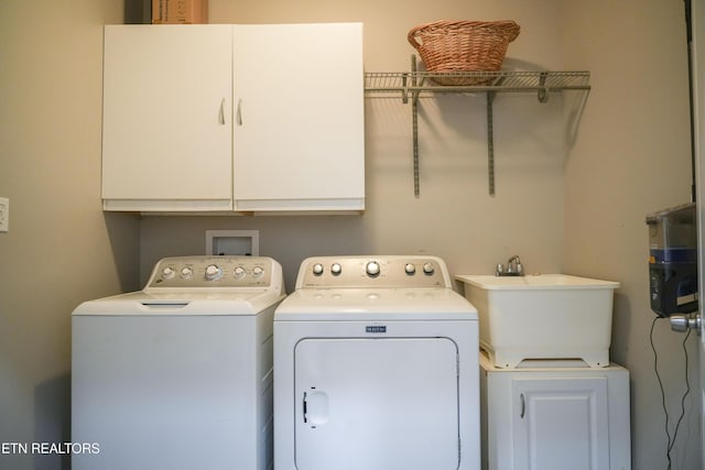 laundry room featuring washer and dryer, cabinet space, and a sink