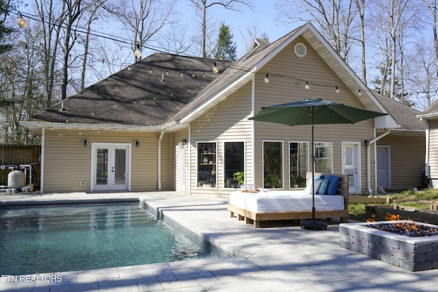 rear view of property featuring an outdoor pool, french doors, a patio, and a fire pit