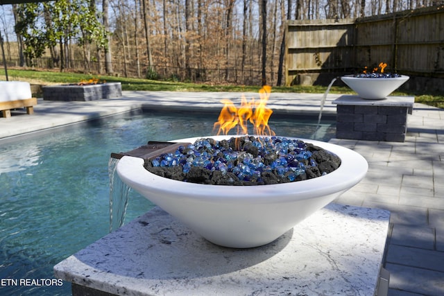 view of swimming pool featuring a fenced in pool, a fire pit, and fence