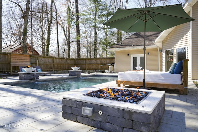 view of swimming pool featuring a patio, a fenced in pool, fence, an outdoor fire pit, and french doors