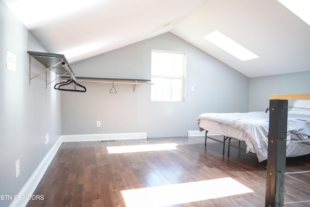 bedroom with baseboards, wood-type flooring, visible vents, and vaulted ceiling with skylight