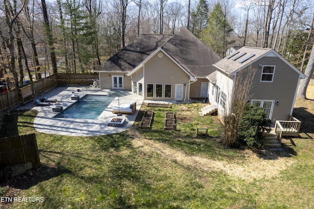 rear view of property with a fenced backyard, french doors, a yard, a fenced in pool, and a patio area