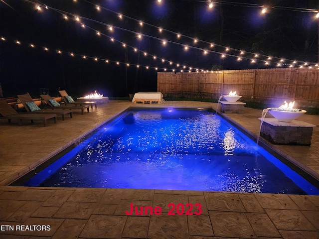 pool at twilight featuring a patio area, a fenced in pool, a fire pit, and fence