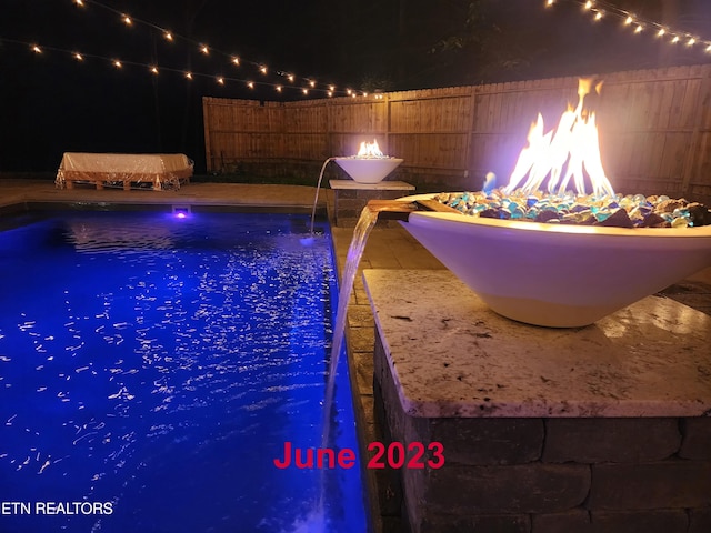 pool at twilight featuring a fenced in pool and a fenced backyard