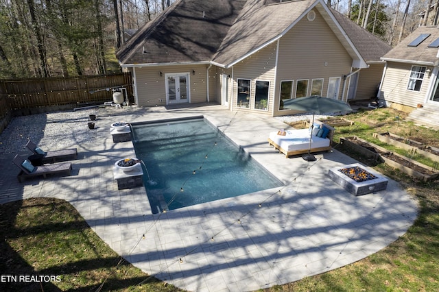 view of swimming pool featuring a patio, a fenced in pool, a fenced backyard, a fire pit, and french doors