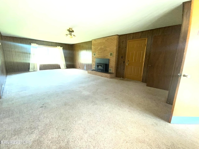 unfurnished living room with visible vents, wood walls, and carpet