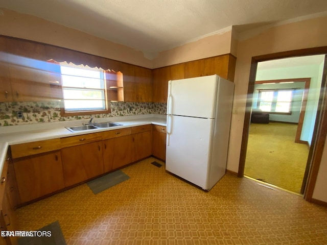 kitchen featuring a sink, open shelves, light countertops, and freestanding refrigerator