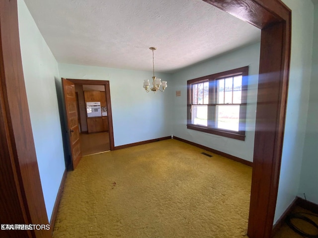 empty room with visible vents, baseboards, a textured ceiling, and an inviting chandelier