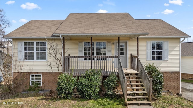 view of front of property with stairway, brick siding, a porch, and a shingled roof