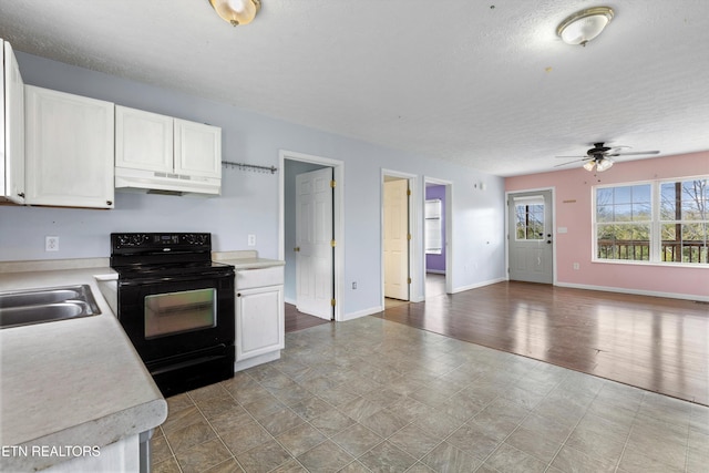 kitchen featuring under cabinet range hood, open floor plan, light countertops, electric range, and white cabinetry