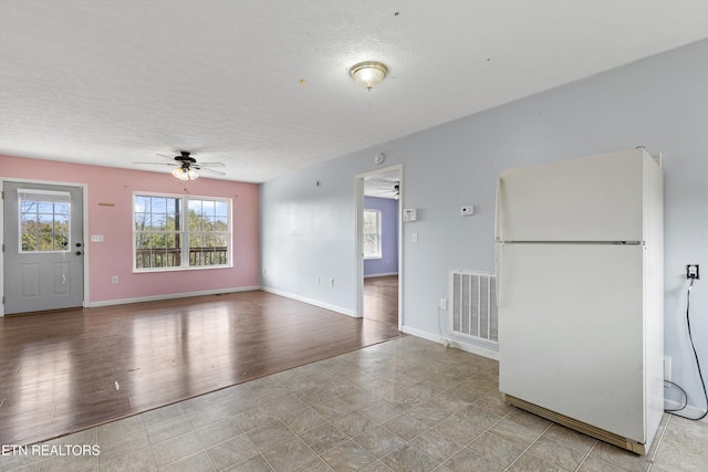 spare room with visible vents, a ceiling fan, a textured ceiling, wood finished floors, and baseboards