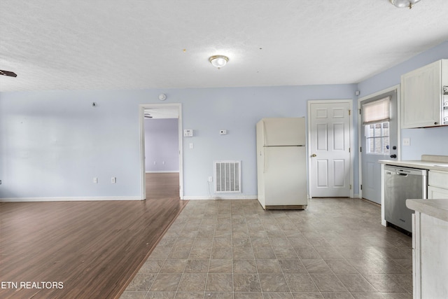 interior space featuring baseboards, visible vents, freestanding refrigerator, light countertops, and dishwasher