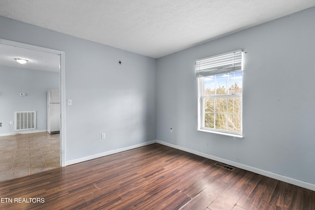 unfurnished room with visible vents, baseboards, and wood finished floors