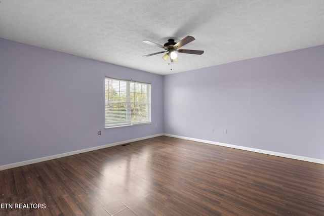 spare room with dark wood-type flooring, a ceiling fan, baseboards, and a textured ceiling