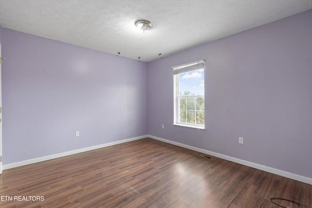 spare room featuring visible vents, baseboards, a textured ceiling, and wood finished floors