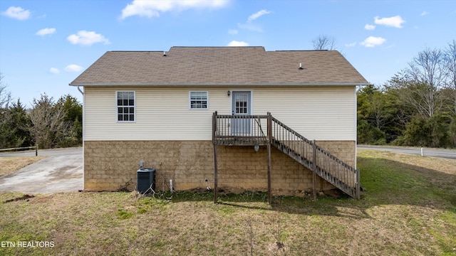 rear view of house with stairway, a lawn, roof with shingles, and cooling unit