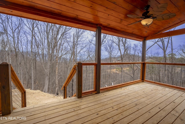 wooden terrace with a wooded view and a ceiling fan