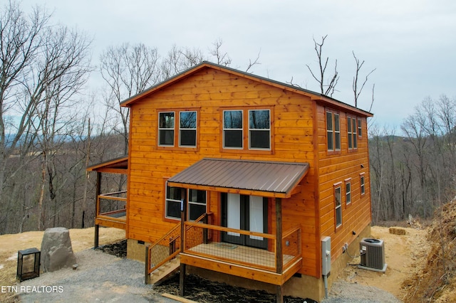 view of front of property with a forest view, central air condition unit, covered porch, metal roof, and crawl space