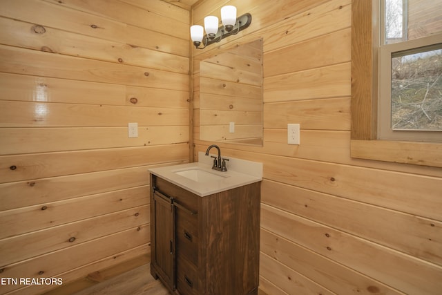 bathroom featuring vanity, an inviting chandelier, and wood walls